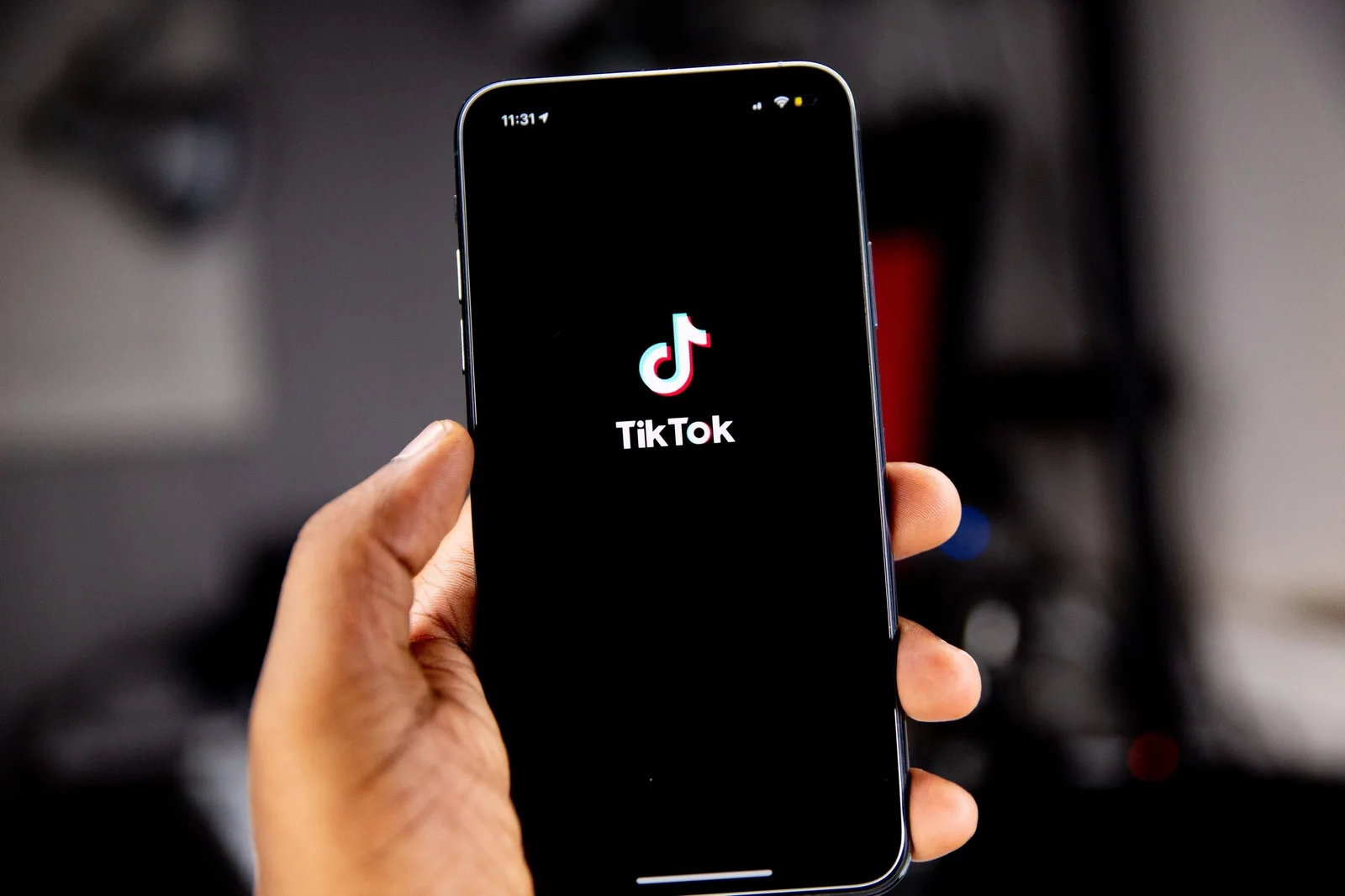 Hand holding a phone displaying the TikTok logo.