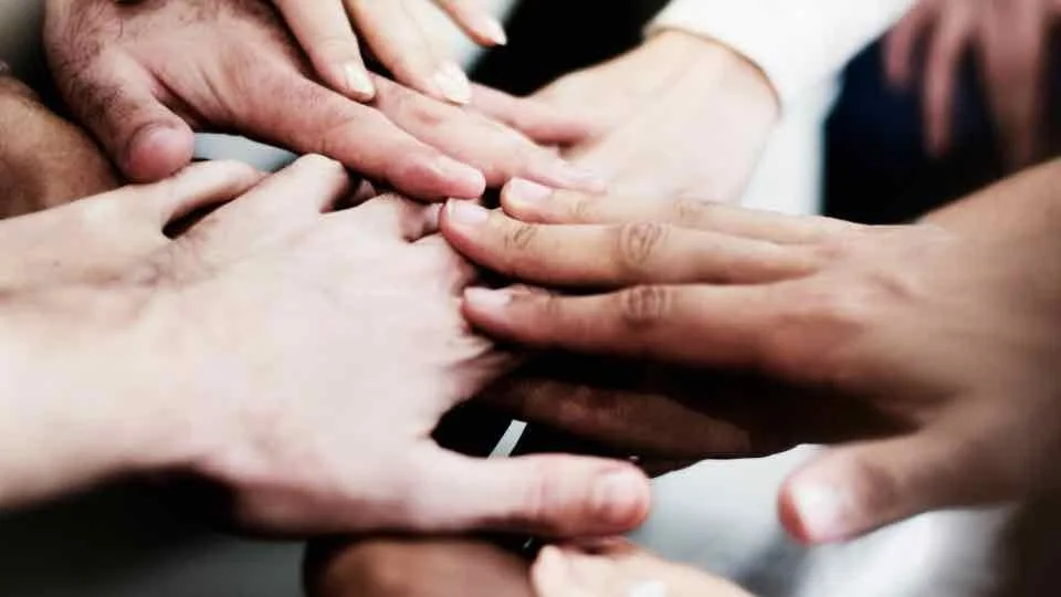 Several people stacking their hands together.