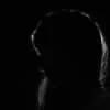 Dark silhouette of a person with their head bowed.