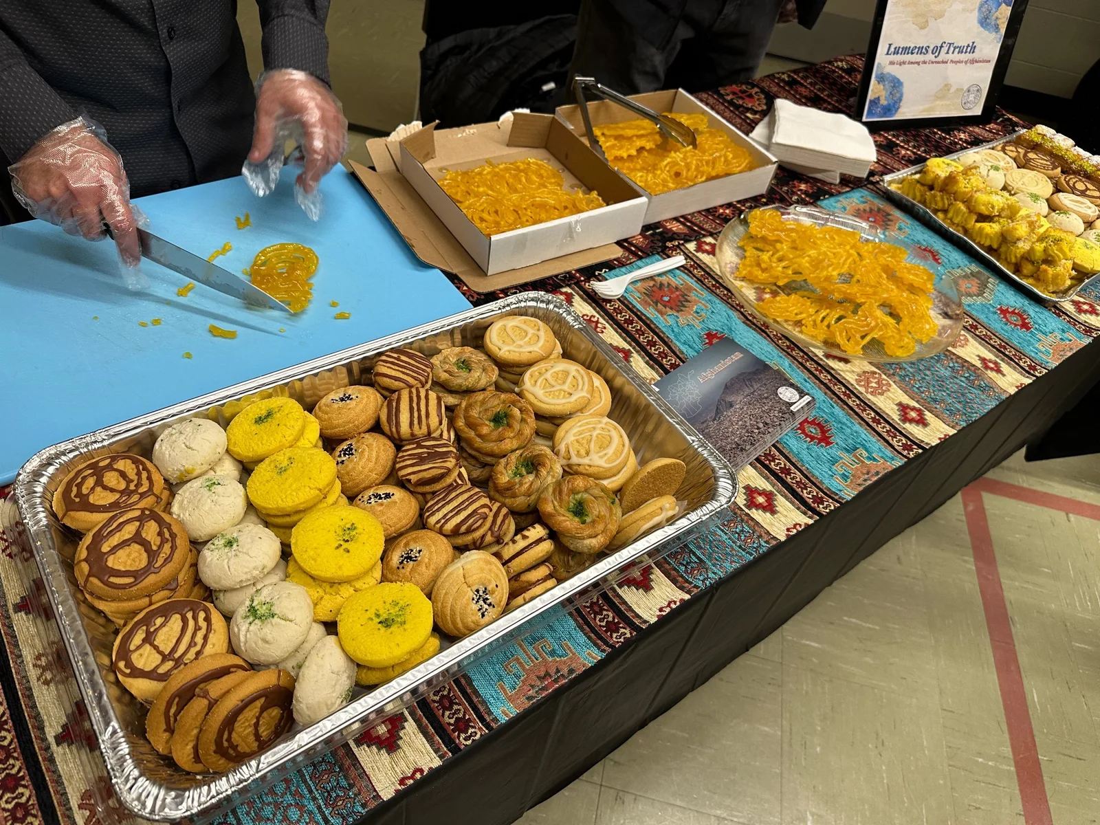 Table filled with trays of pastries and other food.