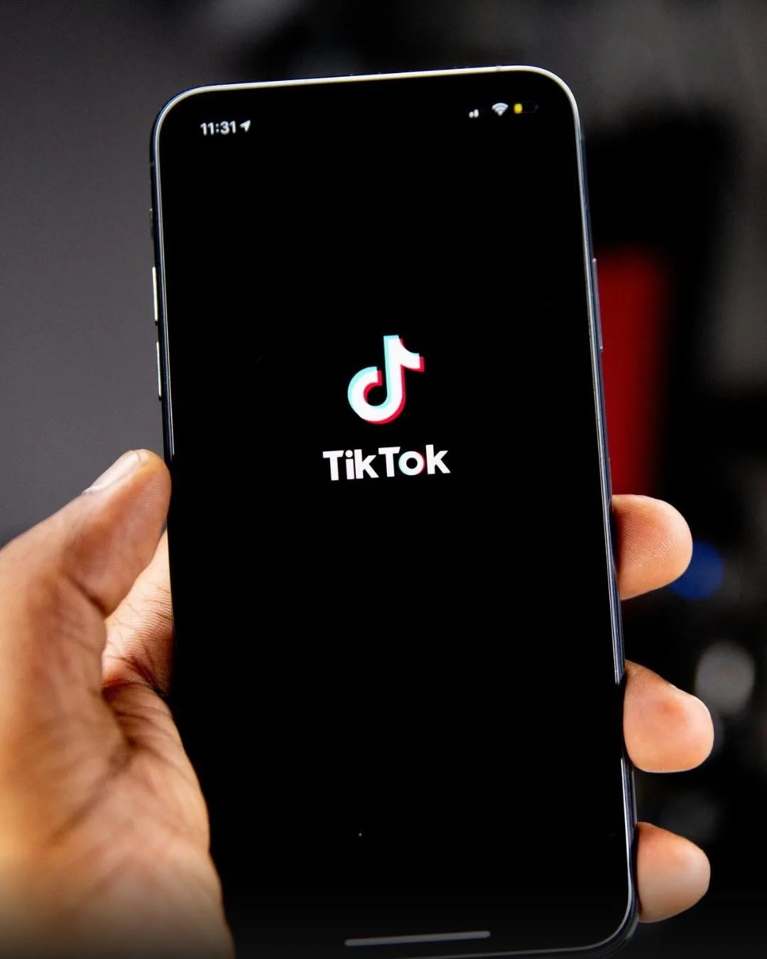 Hand holding a phone displaying the TikTok logo.