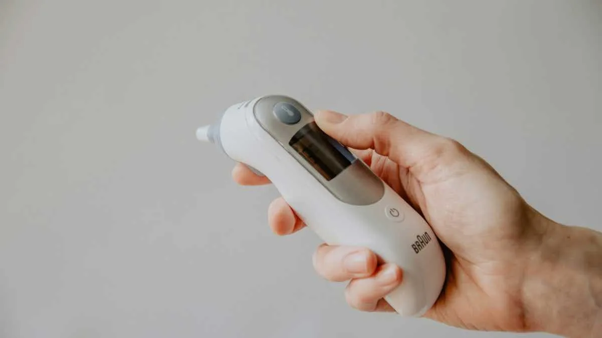 Hand holding a digital thermometer.