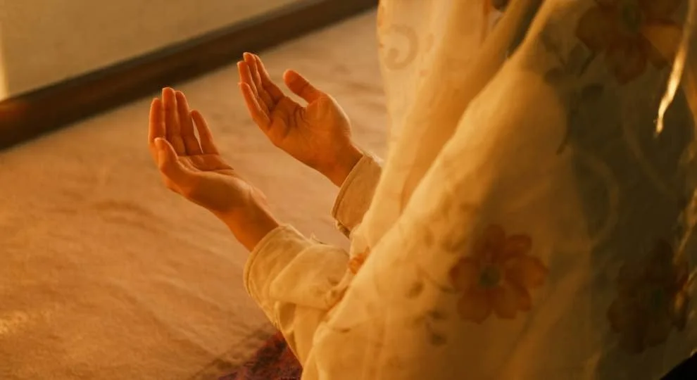 Person holding their palms upward in prayer.