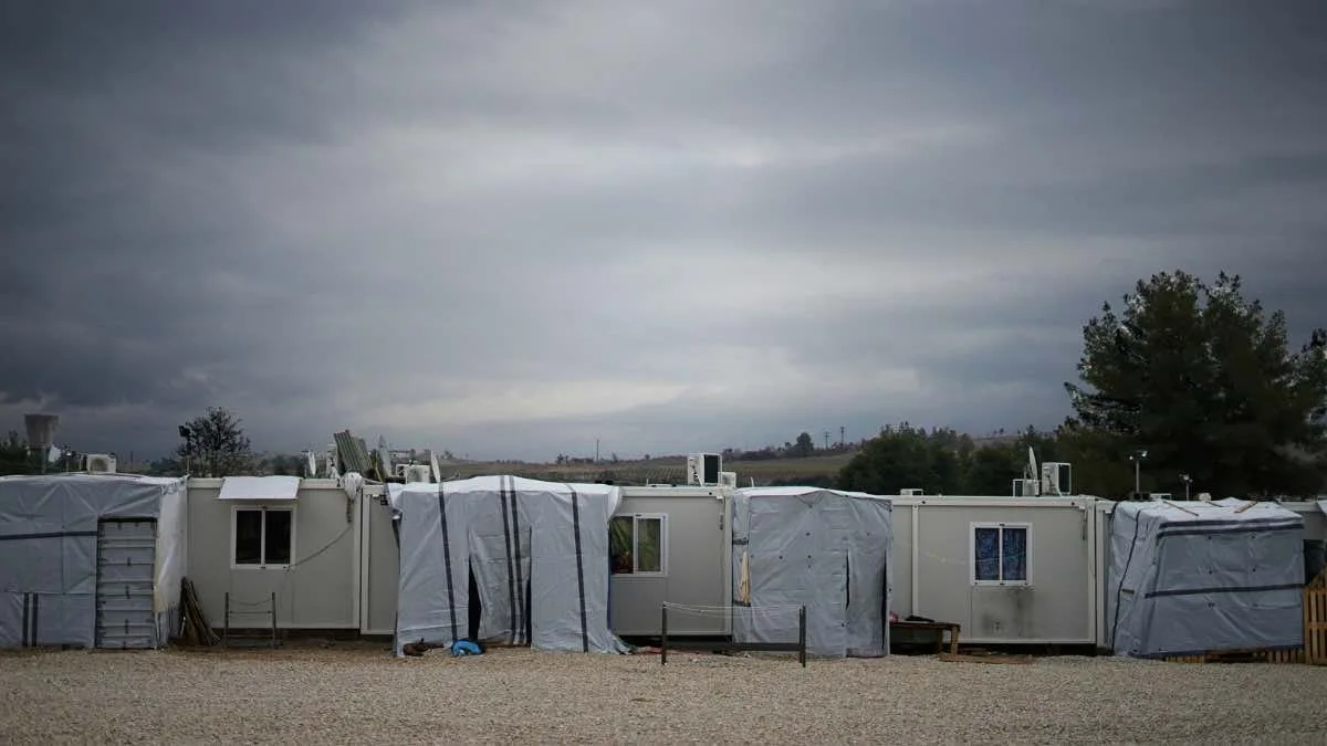 Row of temporary shelters beneath a cloudy sky.