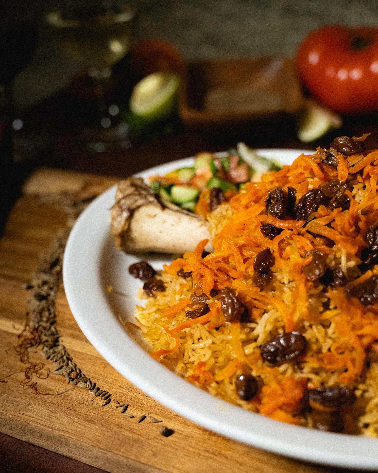Plate of rice with carrots and raisins beside pieces of meat.